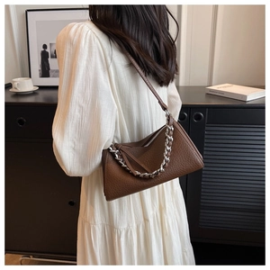Detail of dark brown leather crossbody bag with chunky silver chain and long shoulder strap