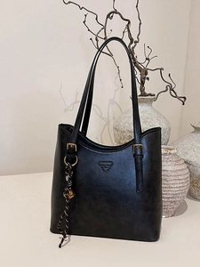 Retro black large capacity tote bag with logo and woven charm on a minimalist background
