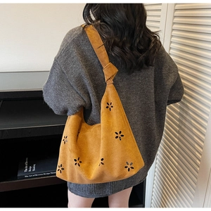 Detail of laser-cut flower pattern on yellow suede tote bag with knotted shoulder strap