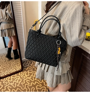Detailed view of black woven bucket bag with elegant beaded tassel and crossbody strap