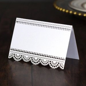 Détail de dentelle découpée au laser sur carte de table papillon blanche sur bois sombre