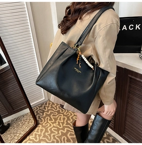 Détail du sac cabas en cuir noir avec design plissé et breloque en perles colorées