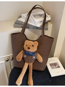 Brown large capacity tote bag with cute plush teddy bear charm in home setting
