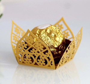 Macro shot of gold laser-cut镂空 floral chocolate wrapper on white reflective surface