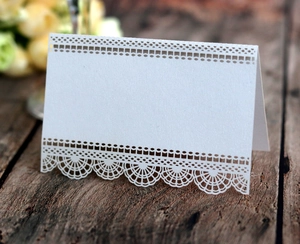 Détail de marque-place de mariage blanc ajouré au laser sur table en bois vintage