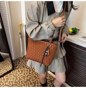 Detail of brown quilted leather bucket bag with colorful beaded tassel pendant