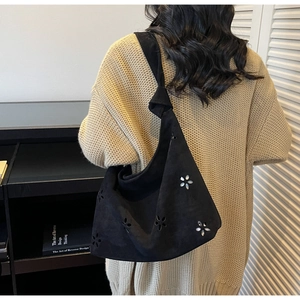 Detail of black matte tote bag featuring intricate floral cutouts and a knotted strap detail