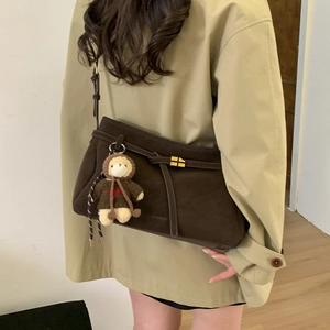 Detail of dark brown suede tote bag featuring a cute bear charm and drawstring buckle