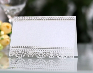 Vue macro d'un marque-place blanc découpé au laser avec motif dentelle et finition nacrée