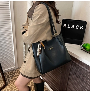 Vue détaillée du sac cabas en simili cuir noir avec breloque en perles et logo en métal
