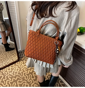 Detail of caramel brown woven bucket bag with beaded tassel and adjustable strap