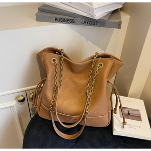 Close-up of brown quilted bucket bag featuring drawstring closure and gold chain strap