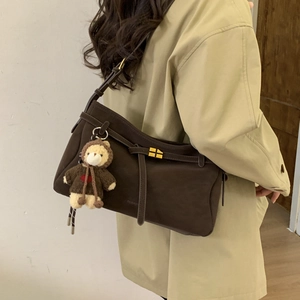 Detail of dark brown minimalist tote bag with plush bear charm on a khaki trench coat