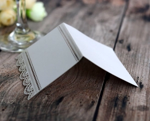Détail de la dentelle découpée au laser sur un marque-place beige pour mariage et fête