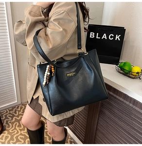 Détail d'un sac cabas noir avec texture en cuir rétro et perles de bois décoratives