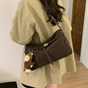 Detail of dark brown suede tote bag featuring a gold square buckle and a cute bear charm