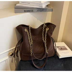 Detail of dark brown leather tote featuring quilted stitching and gold chain strap