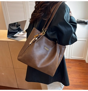 Détail du sac cabas en similicuir marron foncé avec breloque en perles de bois colorées