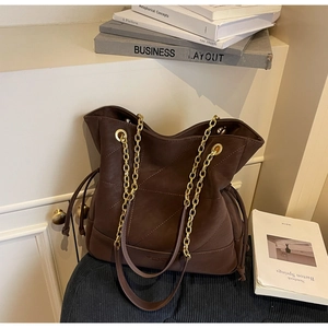 Detail of dark brown tote bag with geometric stitching and thick gold chain strap