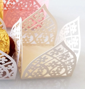 Macro view of laser-cut paper chocolate wrappers with elegant floral hollow patterns