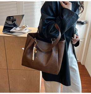 Détail du sac cabas marron foncé avec pendentif à perles ethniques et fini mat