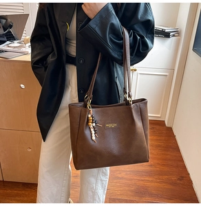 Gros plan du sac cabas marron rétro avec pompon en perles et texture cuir minimaliste