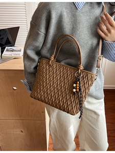 Retro brown textured bucket bag with circular handles and a decorative wooden bead charm