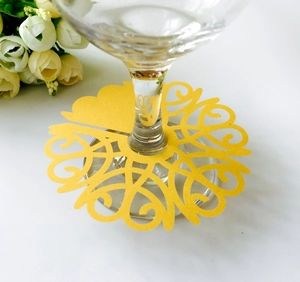 Laser-cut yellow paper wine glass charms with elegant scroll patterns for wedding decor