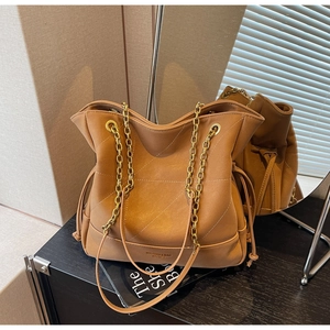 Detail of caramel leather bucket bag with quilted patterns and gold chain strap