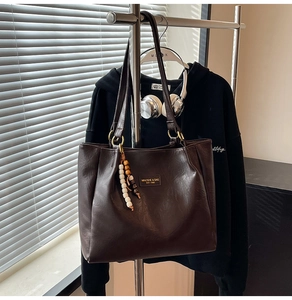Détail du sac cabas marron foncé en simili cuir avec logo et charm en perles colorées