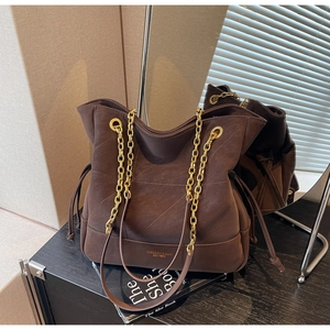 Detail of vintage brown quilted bucket bag featuring gold chain strap and drawstring sides