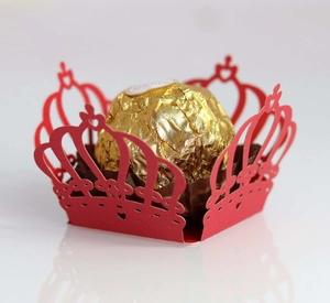 Macro view of red laser-cut crown paper wrapper with heart details for chocolate