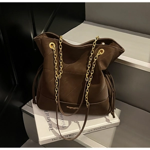 Detail of vintage brown suede bucket bag with gold chain strap and diamond quilting