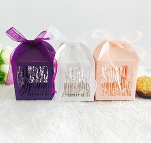Detail of laser-cut bird gift boxes in purple, white, and pink with organza ribbons