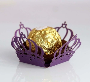 Close-up of laser-cut crown-shaped purple paper lace wrapper for chocolate decoration