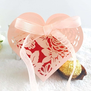 Detail of pink heart-shaped laser-cut wedding favor box with ribbon and rose patterns