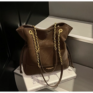 Close-up of brown bucket bag with quilted texture and gold metal chain strap detail