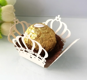 Close-up of laser-cut crown paper cupcake wrapper with heart patterns for weddings
