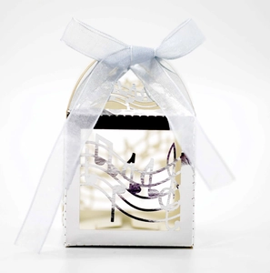 Detail of laser-cut musical note pattern on white wedding favor box with blue ribbon bow