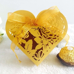 Detailed laser-cut rose patterns on a heart-shaped yellow wedding candy box with ribbon