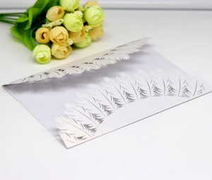 Detailed macro view of laser-cut white pearl paper wedding invitation with feather patterns