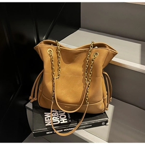 Detail of vintage brown bucket bag with quilted patterns and gold chain strap on grey steps