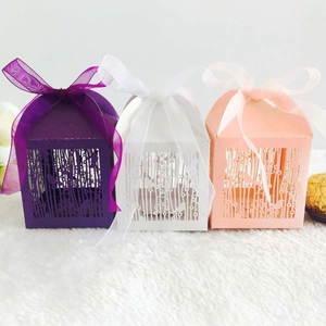 Laser-cut party candy boxes featuring bird and forest silhouettes with organza ribbons