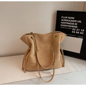 Detail of champagne gold bucket bag with quilted patterns and elegant metal chain strap