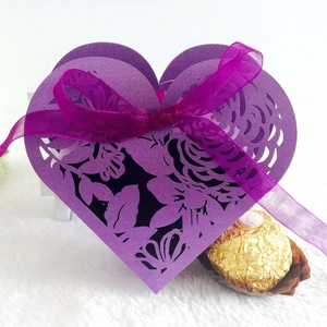 Macro detail of purple heart-shaped cutout wedding favor box with ribbon and lace pattern