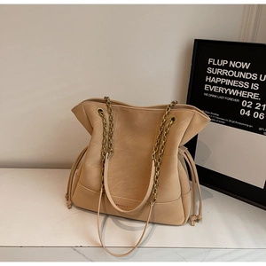 Detail of beige bucket bag with chain strap and geometric stitching on leather