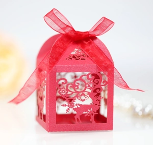 Detail of red laser-cut Christmas favor box with reindeer snowflake design and ribbon