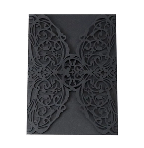 Close-up of black laser-cut wedding invitation sleeve with intricate vine pattern
