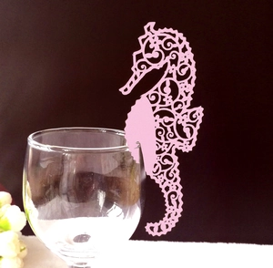 Pink seahorse place card with laser-cut hollow design on a wine glass rim