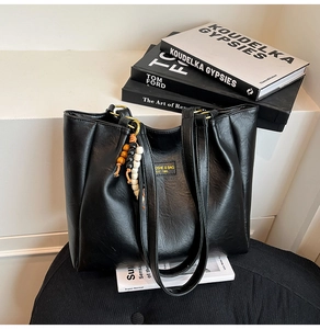Gros plan du sac cabas noir texturé avec pendentif en perles de bois et logo minimaliste
